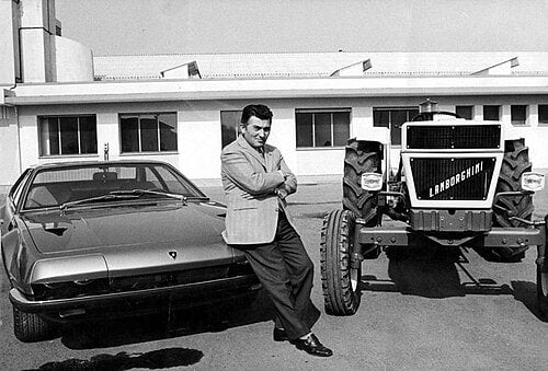 LAMBORGHINI : Ferruccio Lamborghini entre un tracteur et une de ses voitures, vers 1970, domaine public